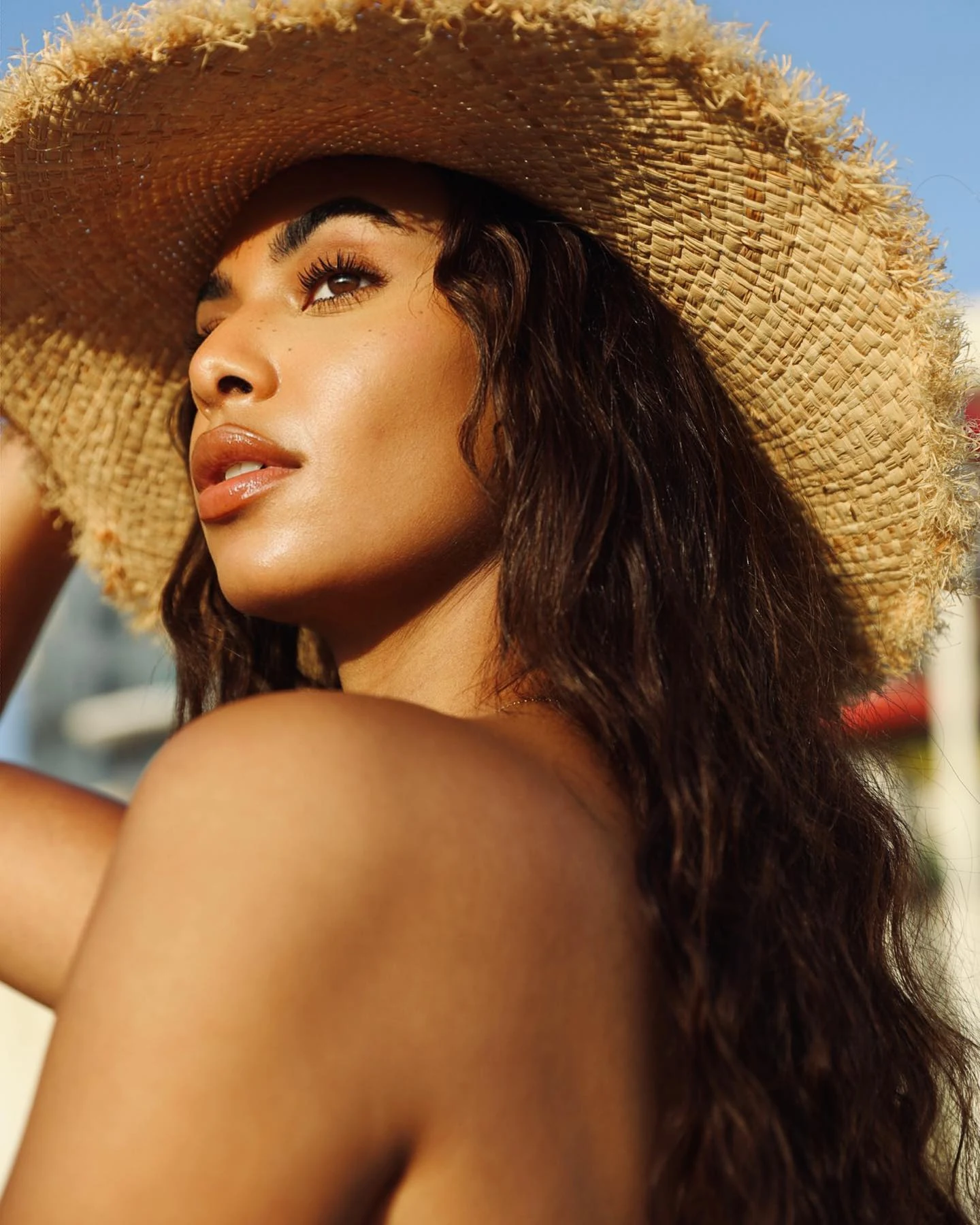 A woman in a woven hat turns toward the morning light.